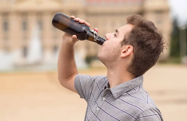 Junger Mann trinkt eine Flasche Bier im Park — Stockfoto