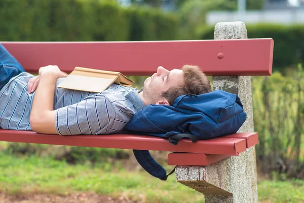 Joven durmiendo en el parque con un libro — Foto de Stock
