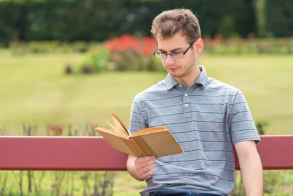 Νεαρός διαβάζει ένα βιβλίο στο πάρκο. — Φωτογραφία Αρχείου