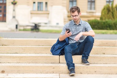Onun telefon ile merdivenlerde oturan genç adam