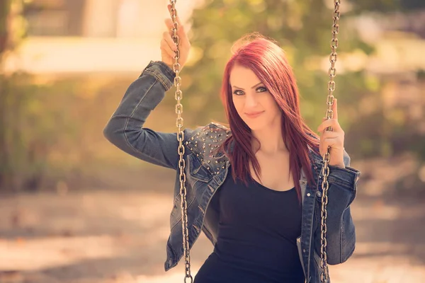 Attractive woman sitting on swing in the park — Stock Photo, Image