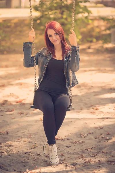 Attractive woman sitting on swing in the park — Stock Photo, Image