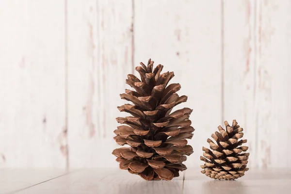 Cone de pinho grande e pequeno no fundo de madeira — Fotografia de Stock