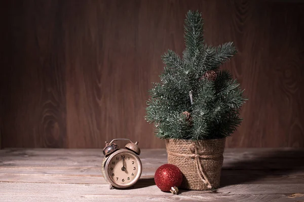 Маленькая сосна и старые часы на деревянном столе — стоковое фото