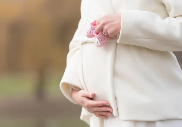 Vrouwelijke hand met een baby schoenen — Stockfoto