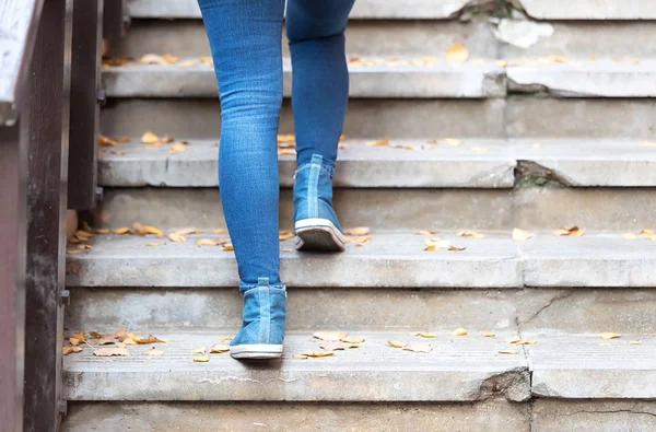 Donna gambe in jeans blu e scarpe blu salendo le scale — Foto Stock