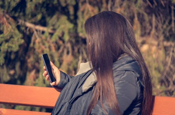 長い髪の女性は公園で彼女の携帯電話を使用します — ストック写真