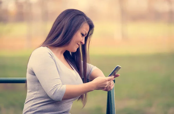 Mujer sentada en un marco de escalada y usar su teléfono — Foto de Stock