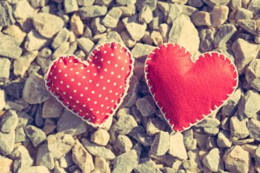 Stitched red hearts on a gravel background