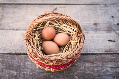 Sepette samanlıkta yatan üç tavuk yumurtası. en üstteki görünüm