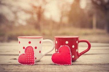 Ahşap bir masada üzerinde aşk sembolü olan kırmızı benekli kupa.