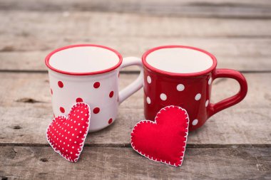 Ahşap bir masada üzerinde aşk sembolü olan kırmızı benekli kupa.