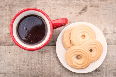 Kırmızı benekli fincanda, üzerinde bisküvi olan siyah çay.