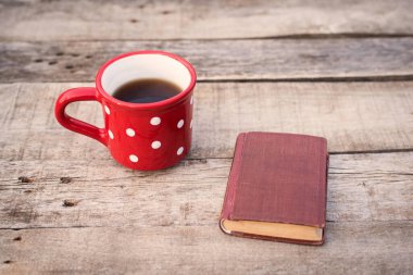 Ahşap zemin üzerinde çay olan eski bir kitap.