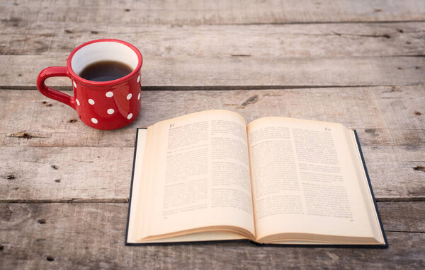 Old book with tea on a wooden background