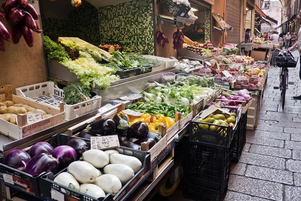 Bolonha, Itália, 16 de junho de 2017 Vegetais sazonais e frutas nas barracas do mercado de rua aberta no centro histórico de Bolonha com pessoas ambulantes e um homem com bicicleta ao fundo — Fotografia de Stock