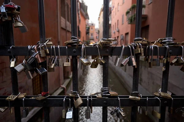 Bologna, İtalya-31 Ocak 2020: Moline Kanalı 'ndaki kapıda asılı duran asma kilitler Bologna' nın tarihi merkezinde, sadık ve sonsuz aşkın bir sembolü olan Oberdan 'da. Ön planda asma kilit, arka planda Moline kanalı.