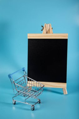  Mavi arka planda boş siyah tahtası olan boş market arabası