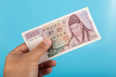 Elinde 1000 won tutan adam mavi arka planlı Güney Kore Bills.