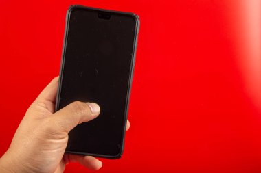 Akıllı telefonu tutan adam kırmızı arkaplanda izole edildi