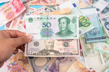 Man Hand, Yuan RMB 'nin Banka Notu ve dünya banknotları koleksiyonu ile birlikte masadan, üst görünüm. İş ve finans kavramı.