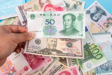 Man Hand, Yuan RMB 'nin Banka Notu ve dünya banknotları koleksiyonu ile birlikte masadan, üst görünüm. İş ve finans kavramı.
