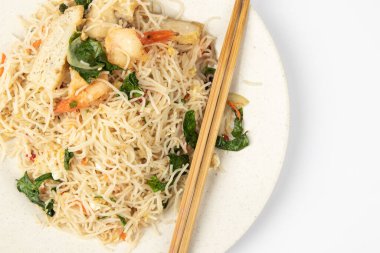 Beyaz arka planda taze karides ve sebzeli ev yapımı balık soslu kızarmış arı paçası..