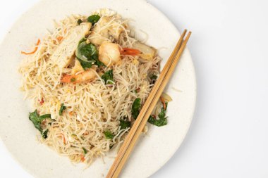 Beyaz arka planda taze karides ve sebzeli ev yapımı balık soslu kızarmış arı paçası..