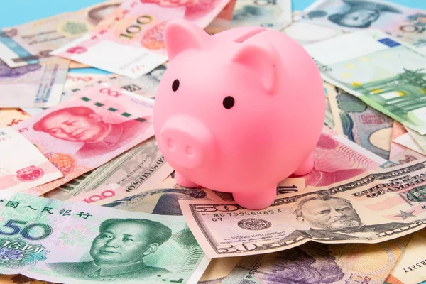 Piggy Bank ve World banknotları koleksiyonu masanın üstünde, en üstte. İş ve finans kavramı.