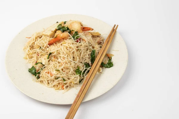 Beyaz arka planda taze karides ve sebzeli ev yapımı balık soslu kızarmış arı paçası..