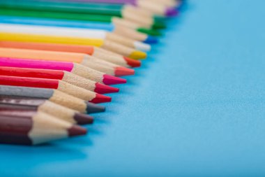 Mavi arkaplanda fotokopi alanı olan renkli kalemlerin yakın plan görüntüsü