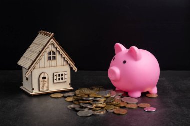 Bozuk para yığını, ev modeli olan domuz kumbarası ev almak için para biriktiriyor. Gayrimenkul yatırımı finans ve bankacılık