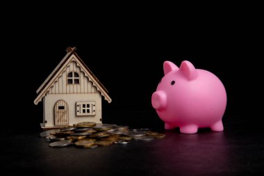 Bozuk para yığını, ev modeli olan domuz kumbarası ev almak için para biriktiriyor. Gayrimenkul yatırımı finans ve bankacılık