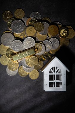 İçinde ev modeli olan bozuk para yığını ev almak için para biriktiriyor. Gayrimenkul yatırımı finansman ve bankacılık