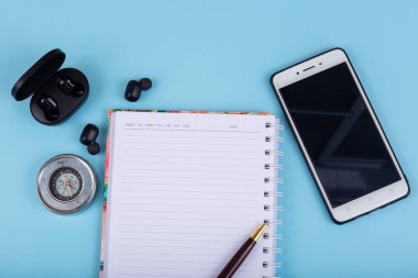 Not Defteri, Akıllı Telefon, Kablosuz Bluetooth kulaklık ve mavi arka planda pusula.