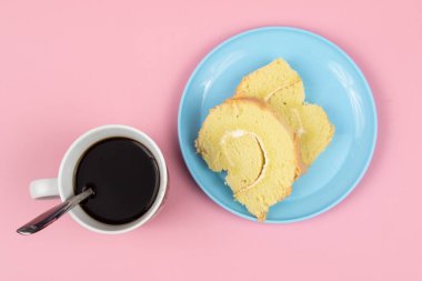 Pembe arka planda bir fincan kahveli İsviçre usulü kek..