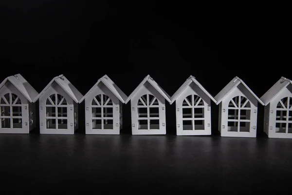 White wooden house model in a row on black backgrounf