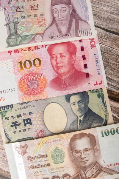将泰铢 韩元和中国元的肖像钞票贴在木制背景上 金融和商业概念 — 图库照片