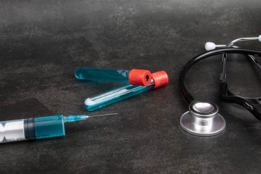 Aşı ve siyah arka planda diğer tıbbi ekipmanlarla birlikte bir şırınga.. 