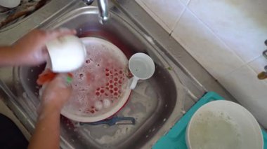 Kadın elleri ev işi yapıyor. Lavaboda bulaşıkları elle yıkıyor.