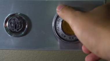 Adam eli, eski kasa şifresini açıyor tuşları çeviriyor.