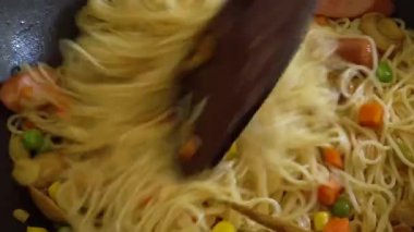 Yerel hayat tarzı ev hanımı öğle yemeği için evde kızarmış erişte pişiriyor.