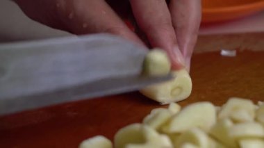 Sarımsak kesmek için bıçak kullanan bir adam.