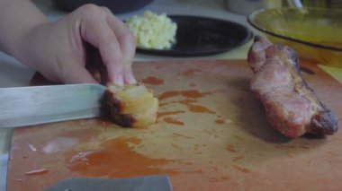Kesme tahtasındaki Char Siew etini dilimlemek için bıçak kullanan kadın elleri görüntüsü.