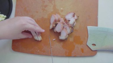 Kesme tahtasındaki Char Siew etini dilimlemek için bıçak kullanan kadın elleri görüntüsü.