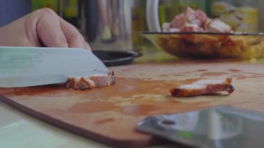 Kesme tahtasındaki Char Siew etini dilimlemek için bıçak kullanan kadın elleri görüntüsü.