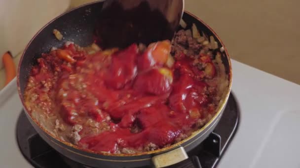 femme au foyer cuisine du bœuf haché avec sauce tomate sur une poêle chaude .