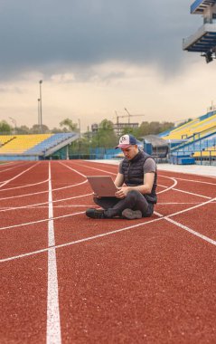 Dizüstü bilgisayarı olan adam stadyumda oturuyor, programcı da boş stadyumda. Alışılmadık yerlerde çalışmak