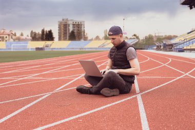 Dizüstü bilgisayarı olan adam stadyumda oturuyor, programcı da boş stadyumda. Alışılmadık yerlerde çalışmak
