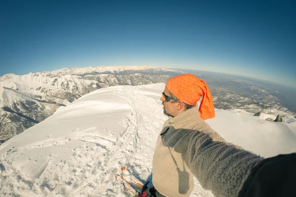 Pro dospělé alpin lyžař plnovous, sluneční brýle a klobouk, přičemž selfie na zasněženém svahu v krásné Italské Alpy s jasnou modrou oblohu. Tónovaný obrázek, vintage styl, širokém pozorovacím úhlu fisheye objektivu. — Stock fotografie